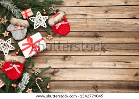 Christmas tree branches with gift boxes and gloves on brown wooden table