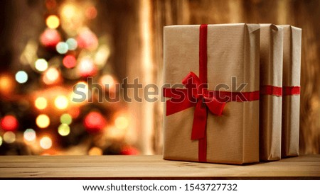 Table background of free space and christmas gifts. Xmas tree and wooden blurred wall. 