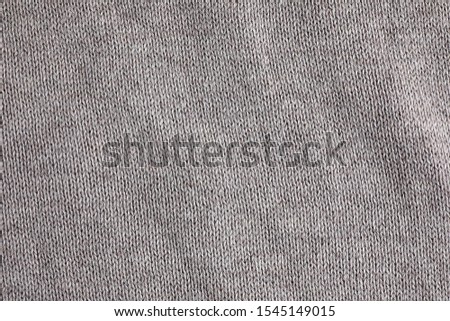 Grey knitted sweater as background, closeup view