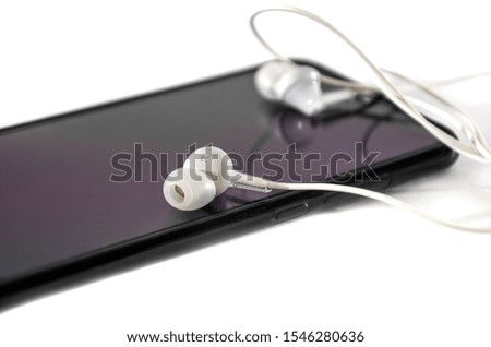 black phone and white headphones on a white background. Close-up.