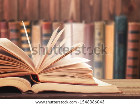 Old open book on a bookshelf background.