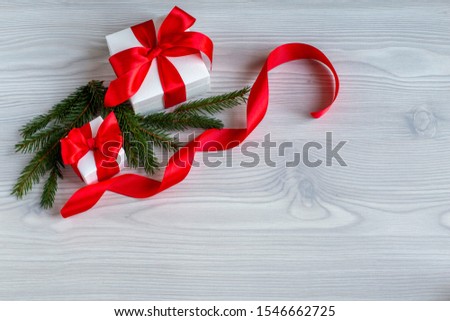 Christmas and  New year  festive composition , fir tree and two gift boxes with red bow on a wooden background . Flat lay, top view. Copy space.