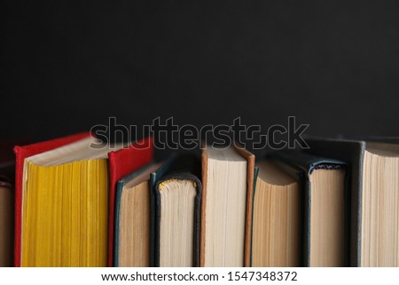 Stack of hardcover books on black background, closeup. Space for text