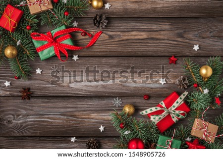 Christmas and Happy New Year background. Fir tree branches with red holiday decorations and gift boxes on rustic wooden table. top view. flat lay with copy space