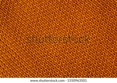 Close-up of an orange knitted fabric from a sweater or other woolen product. The concept of warm cozy products. Handmade product. Place for text