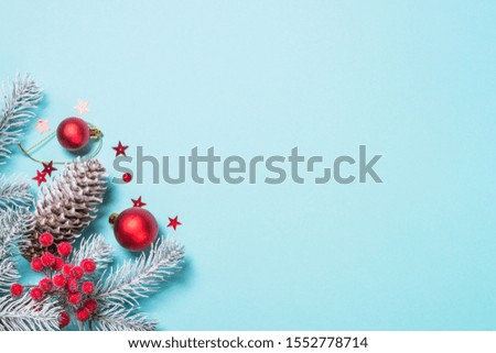 Christmas flat lay background with christmas tree and red decorations on blue. Top view with copy space.