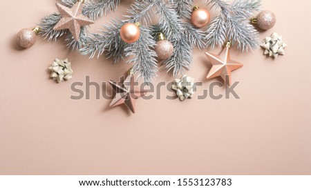 Christmas tree branch with luxury cream color decorations on copper background. Flat lay, top view, copy space. Xmas frame, winter holidays banner mockup, New Year greeting card