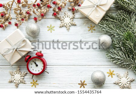 Flat lay composition with alarm clock, pine branches  and Christmas decorations on white wooden background.