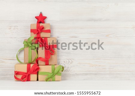 Christmas greeting card with various gift boxes in front of wooden wall with copy space for your greetings