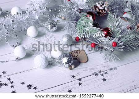 Christmas background from a fir wreath with natural fir cones, which lies on a bleached wooden table next to Christmas toys, snowflakes, stars, beads and rattan balls