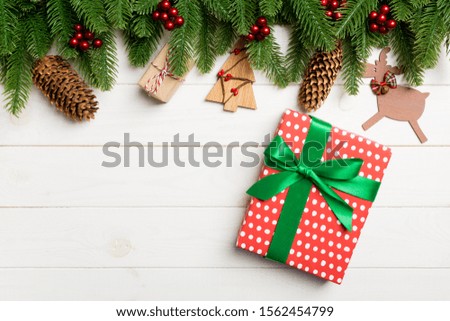 Top view of fir tree, New Year decorations and gift on wooden background. Christmas concept with copy space.