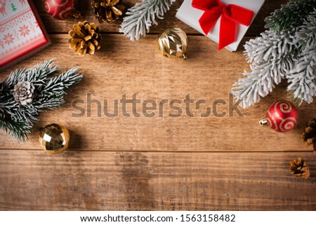 Christmas card with gift, fir branch and balls, gift and decoration on wooden background flat lay