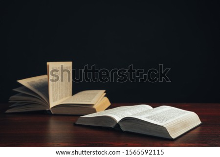 Open bible on a  red wooden table. Beautiful black background.