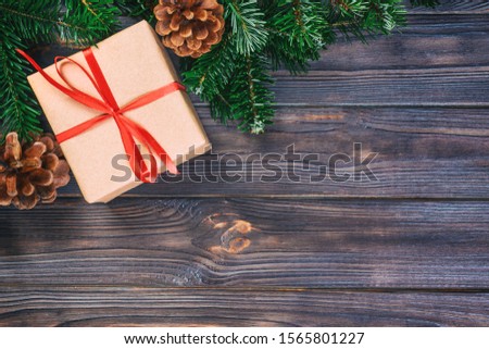 Christmas composition background. Christmas gift with pine cones and fir branches on wooden background. Flat lay, top view, copy space. Toned.