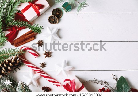 Beautiful Christmas composition on white background with golden Christmas gift boxes, snowy fir branches, conifer cones, holiday decoration and red berry. Top view