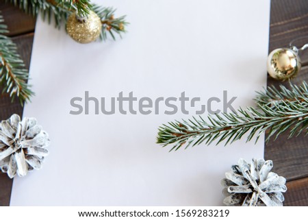 Christmas, decoration on a white table background with a blank white sheet. New Year's pine cones and golden Christmas balls. Place for text.