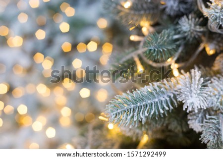 Christmas tree with artificial snow and garlands, fir brunch, bokeh