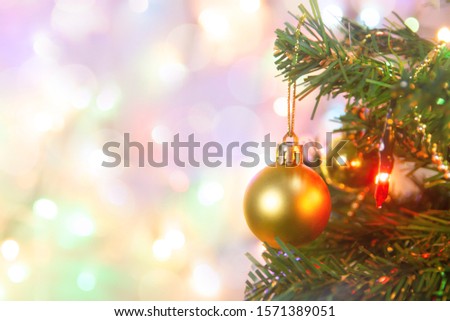 Christmas decoration. Hanging gold balls on pine branches Christmas tree garland and ornaments over abstract bokeh background with copy space
