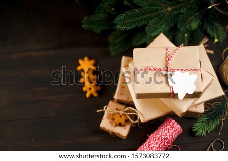 gifts wrapped in craft paper and decorated with homemade gingerbread cookies on dark background, Holidays greeting card, winter Event conception, Template mockup greeting card with Copy space,
