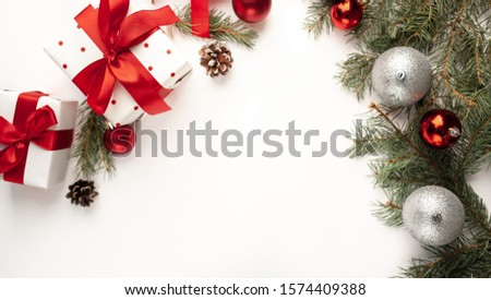 Christmas composition on a white background with white gift boxes, with a red ribbon with fir branches, toys, copy space for your congratulations