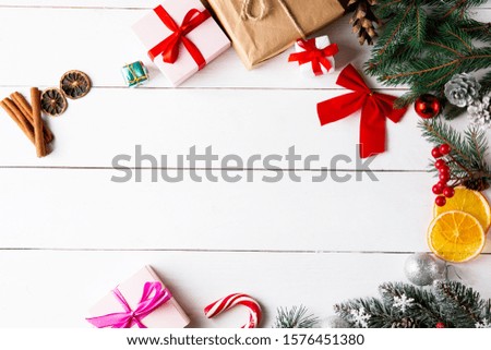 Beautiful Christmas composition on wooden white background with Christmas gift boxes, snowy fir branches, conifer cones,dried fruits, holiday decoration, caramel stick. New Year.Top view, copy space.