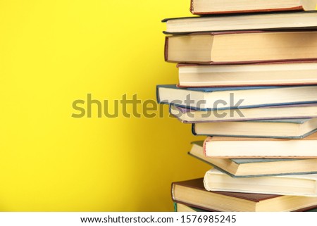 Stack of hardcover books on yellow background. Space for text