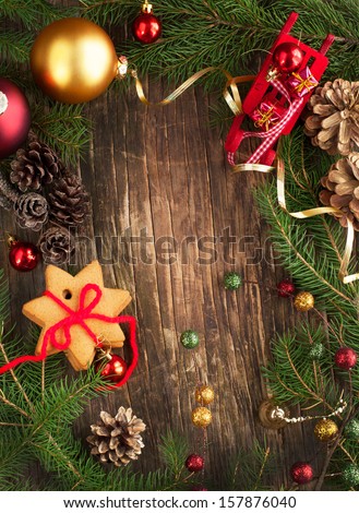 Frame with Christmas tree branches, cookies and ornaments on wooden background