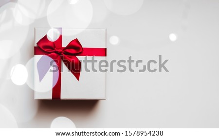 White gift box with red ribbon bow, isolated on white
