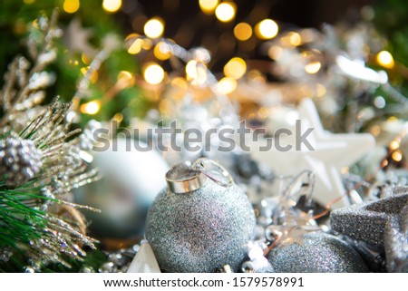 Christmas background. Beautiful bokeh in the background. Wedding rings lie on a Christmas ball