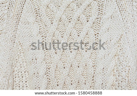 Closeup Beautiful texture of a soft warm natural sweater with a knitted pattern of threads. The background.


