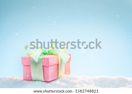 Pastel colored gift in the snow on a winter sunny day.
