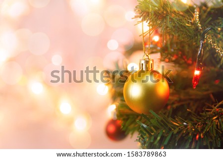 Christmas decoration. Hanging gold balls on pine branches Christmas tree garland and ornaments over abstract bokeh background with copy space
