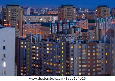 Residential buildings in the evening when the windows light up. Night city, evening city. City blocks, houses on top. Typical city in the evening, standard urban development in Russia. Modern houses
