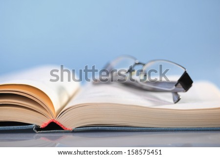 Open book on blue with eyeglasses