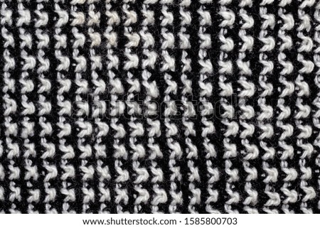 Knitted woolen white and black background. Texture of black and white wool close-up. Knitted fabric, handmade, knitting.