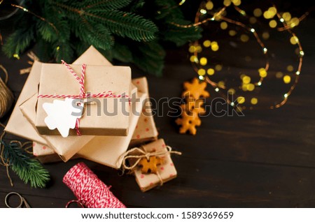 gifts wrapped in craft paper and decorated with homemade gingerbread cookies on dark background, Holidays greeting card, winter Event conception, Template mockup greeting card with Copy space,