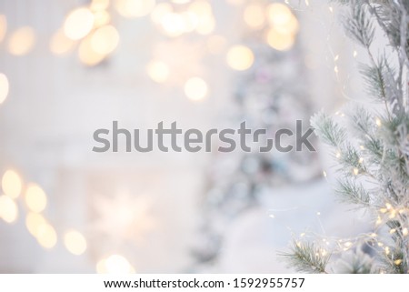 Christmas silver shiny garland hanging on a spruce branch. Lights and garlands on grey, white background Christmas and happy New year concept, space for text for your design. Postcard, blur