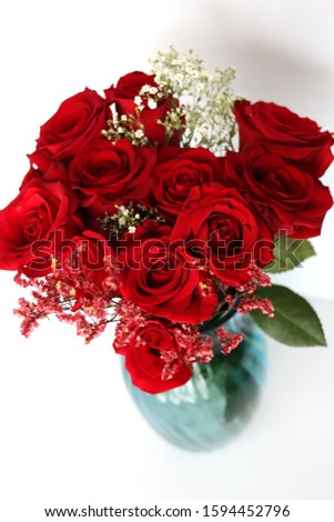 A closeup of red roses in a blue vase on a white background 