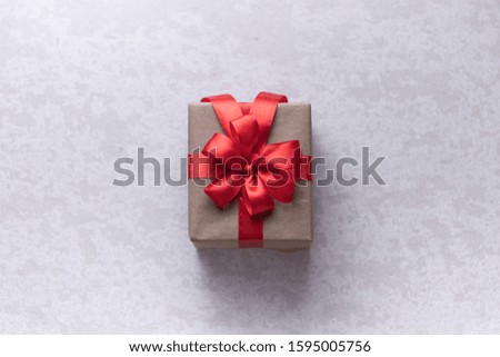 Brown gift box with red ribbon, grey background flat lay for stock image.  