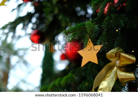Golden stars hanging on a Christmas tree, background blurred with bokeh