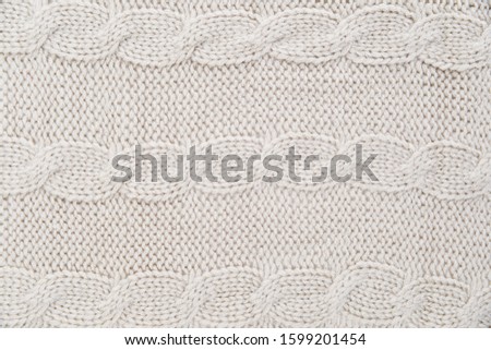 White knitted carpet closeup. Knit cashmere beige wool. Natural woolen fabric, sweater fragment.




