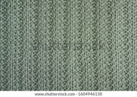 The texture of a gray-green knitted sweater. Openwork knitted elastic band close-up.