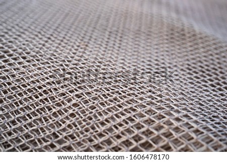 Close up view of fishing net in marine port in the morning. Selective focus. Blurred pattern background.