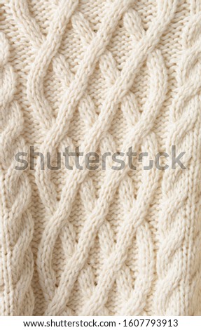 White knitted carpet closeup. Knit cashmere beige wool. Natural woolen fabric, sweater fragment.
