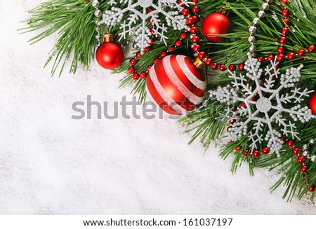 Green pine tree branch with  Christmas balls on snow background