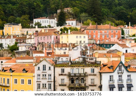 Colorful, historic buildings in hues of yellow, orange, pink, and peach densely clustered on a hillside in Sintra, Portugal