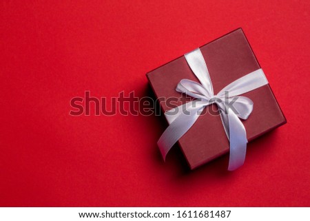 Red gift box with a white bow on red background, Valentine's Day concept, top view, copy space