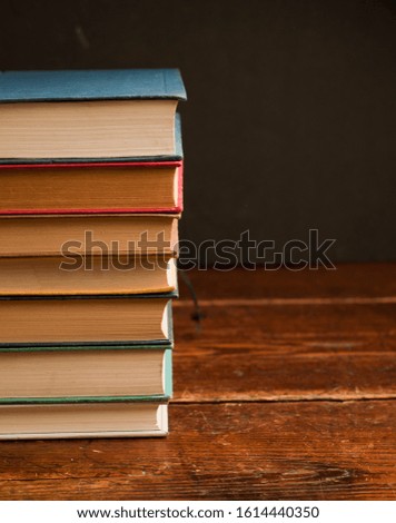 stack of multi-colored books on old wooden shelf with dark background