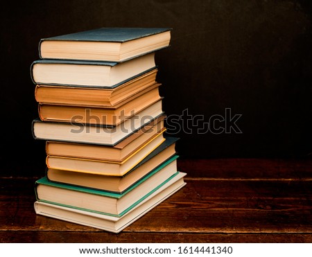 stack of colored books on old wooden shelf with dark background