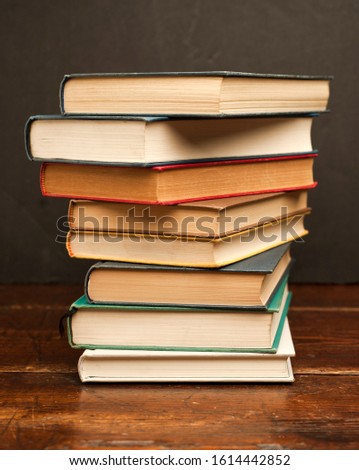 stack of colored vintage books on old wooden shelf with dark background